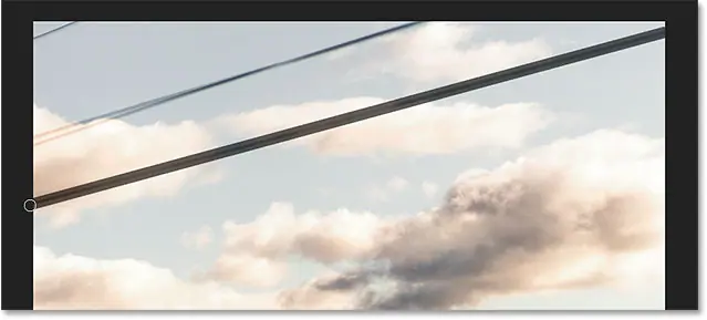 Paint with the Spot Healing Brush over the unwanted wire.