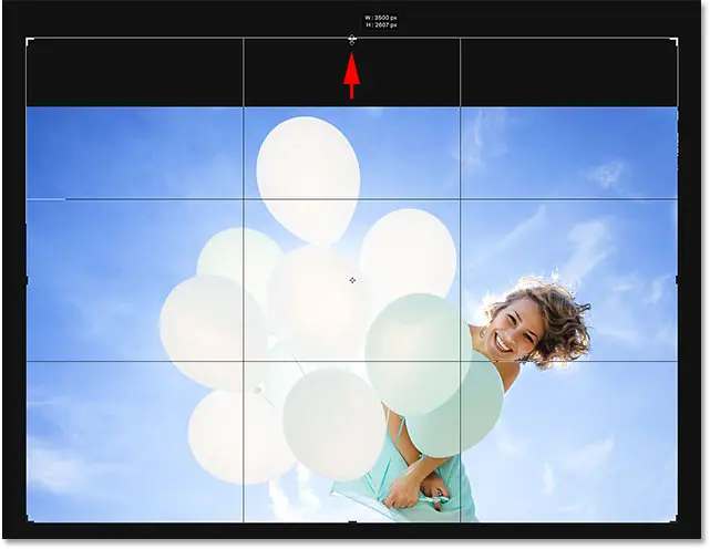 سحب مقبض الاقتصاص لأعلى لإضافة مساحة أكبر فوق الصورة في Photoshop